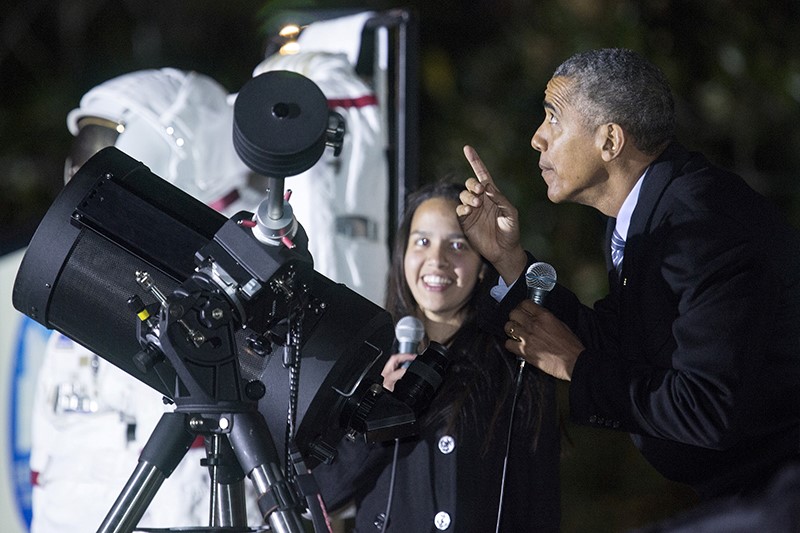 U.S. President Barack Obama points at the moon after looking at it through a telescope with Agatha Sofia Alvarez-Bareiro, a high school senior from Brooklyn, New York, during the second White House Astronomy Night on the South Lawn of the White House in Washington on October 19, 2015. Photo courtesy of Joshua Roberts / Reuters.